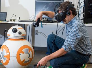 A man wearing VR goggles with a droid
