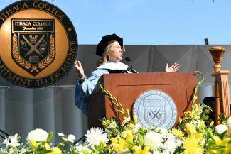 speaker with the Ithaca College seal behind her