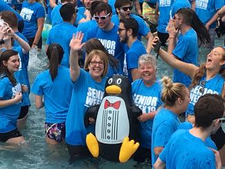 women in a fountain holding an inflatable penguin