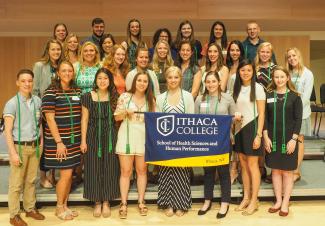 This is a photo of approximately 30 students standing in front of an HSHP banner. These are the students that were awarded the Alpha Eta cords during the HSHP Awards Ceremony.