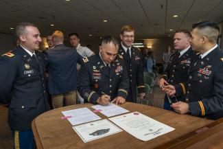ROTC officers gathered around a table signing documents