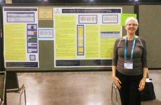 Faculty member Luanne Andersson stands in front of her winning poster on Diagnostic Accuracy of Tests of Children's Language, Speech, Sound Development & Phonological Awareness