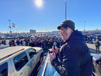man with microphone in front of tailgate party
