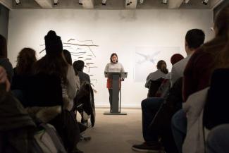 A Writing student stands at a podium in front of a darkened crowd