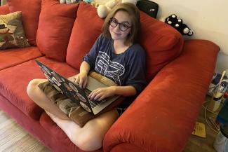 student on couch with laptop
