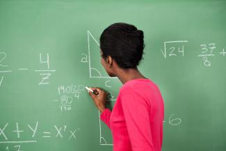 Woman at chalkboard writing math equation