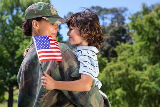 female soldier hugging boy holding US flag