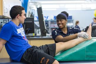 student athletic trainer helping athlete