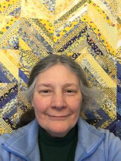 Photo of Bridget in front of yellow and blue quilt