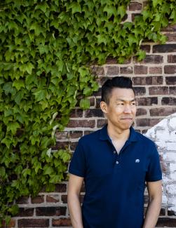 Professor Jack Wang standing against a brick wall with ivy.