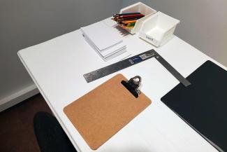 a table with a clipboard, paper and colored pencils