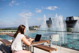 Student on a laptop by the fountains