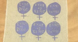 Cloth with repeating Venus symbols that each say Exist to Resist