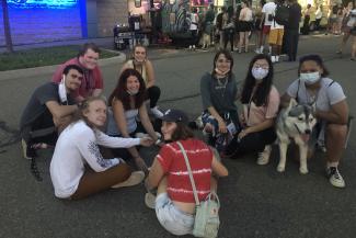 A group of students sitting outside with a dog.