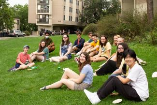 A group of students smiling outside on the grass