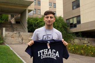Student holding a blue Ithaca College T-Shirt
