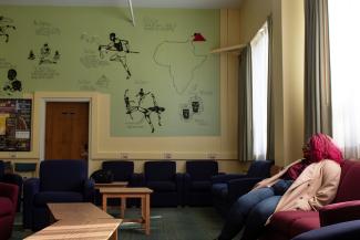 A woman sitting in the ALS room next to the mural