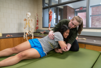 Two students practicing bed mobility