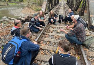 Students sitting on train tracks in a circle