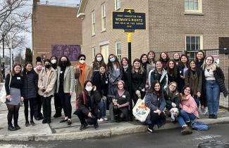 Students in front of a sign marking the location of the first convention for women's right