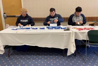 Football players at a table stuffing envelopes