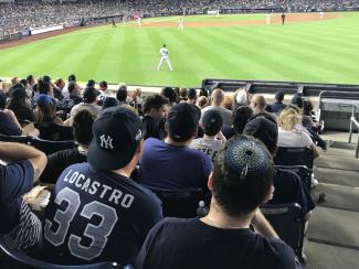 Fan in the stands wearing a Yankee Hat and Locastro jersy
