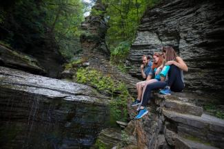 Three students are seated in a gorge looking at the water.
