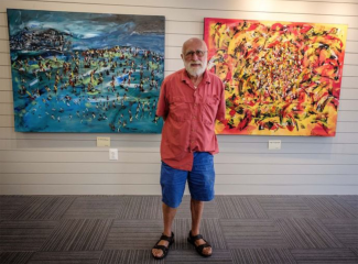 William Collins standing in front of his paintings.