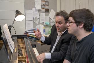 A student is playing piano with a faculty member.