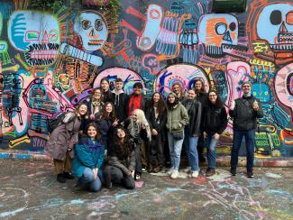 A class poses in front of a street mural