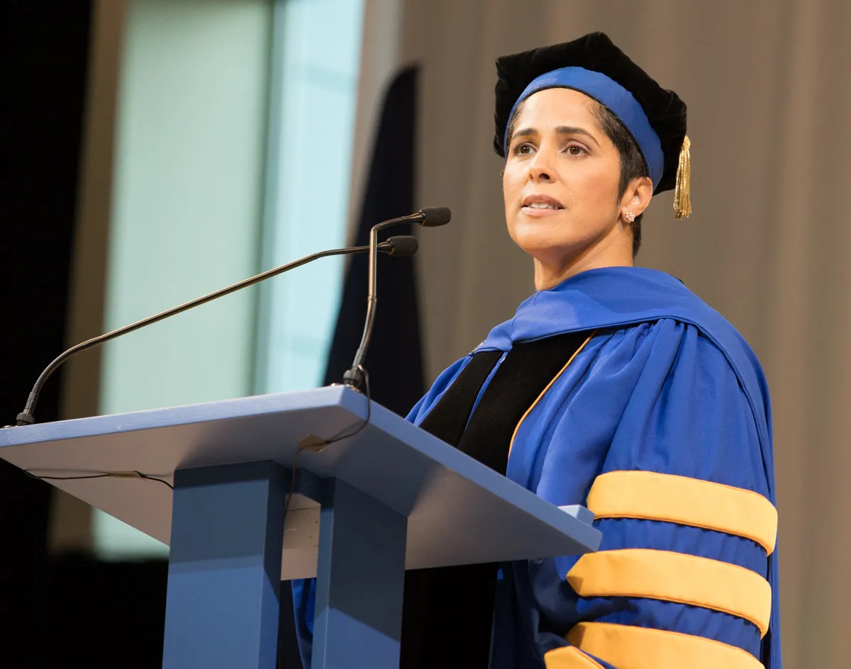 Shirley M. Collado speaking at a podium in academic robes