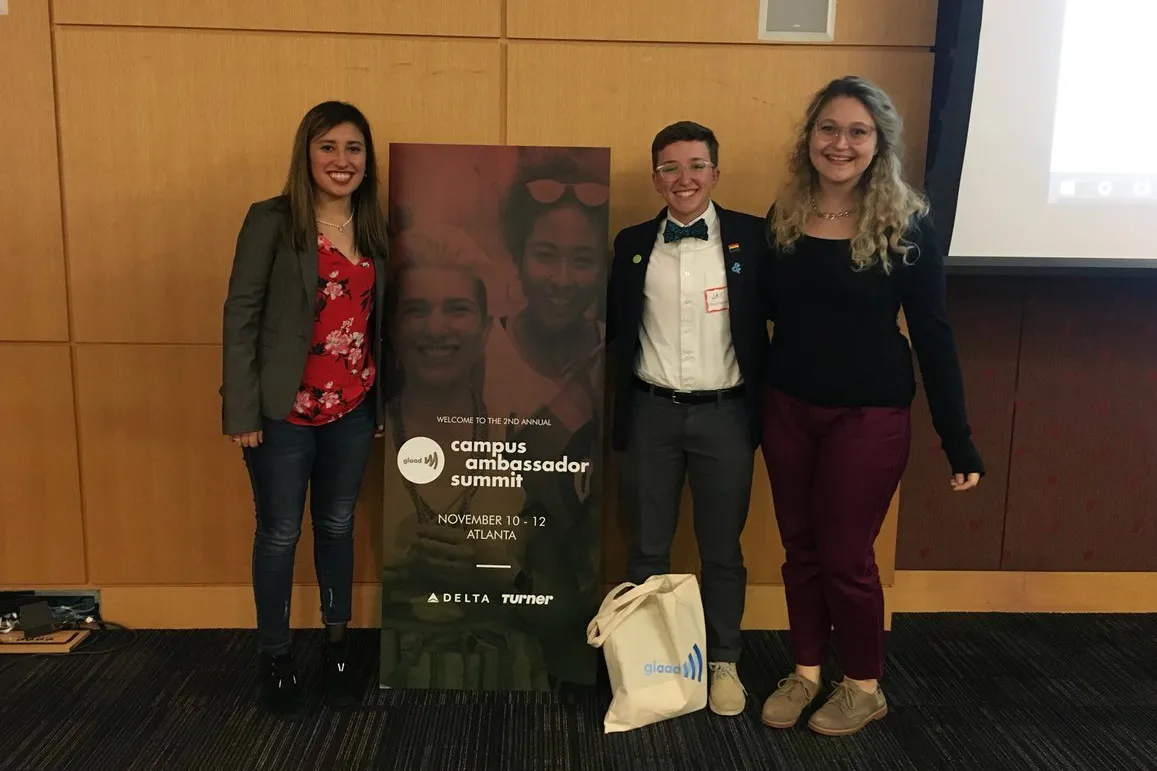 Three women stand next to a banner reading "Campus Ambassador Summit"