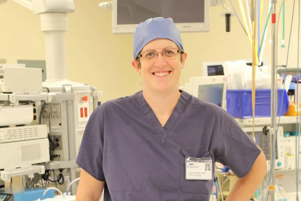 A woman in scrubs stands in a hospital room