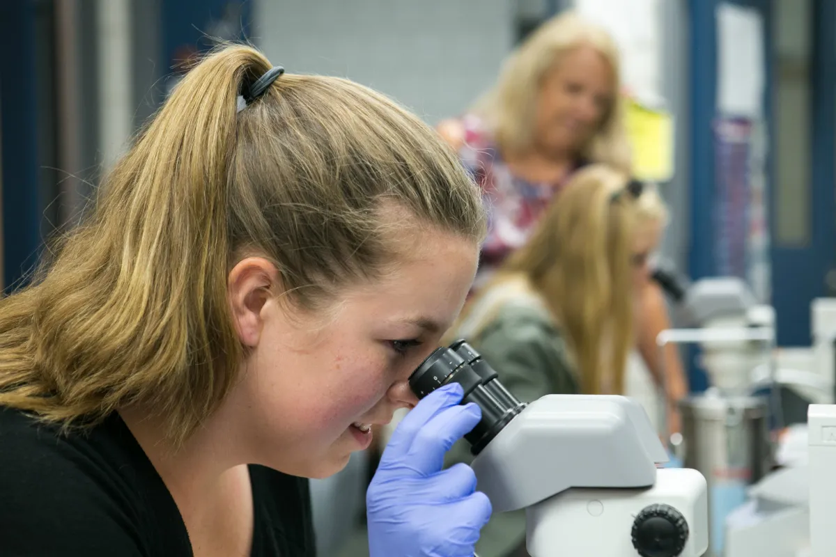 A young woman using a microscope