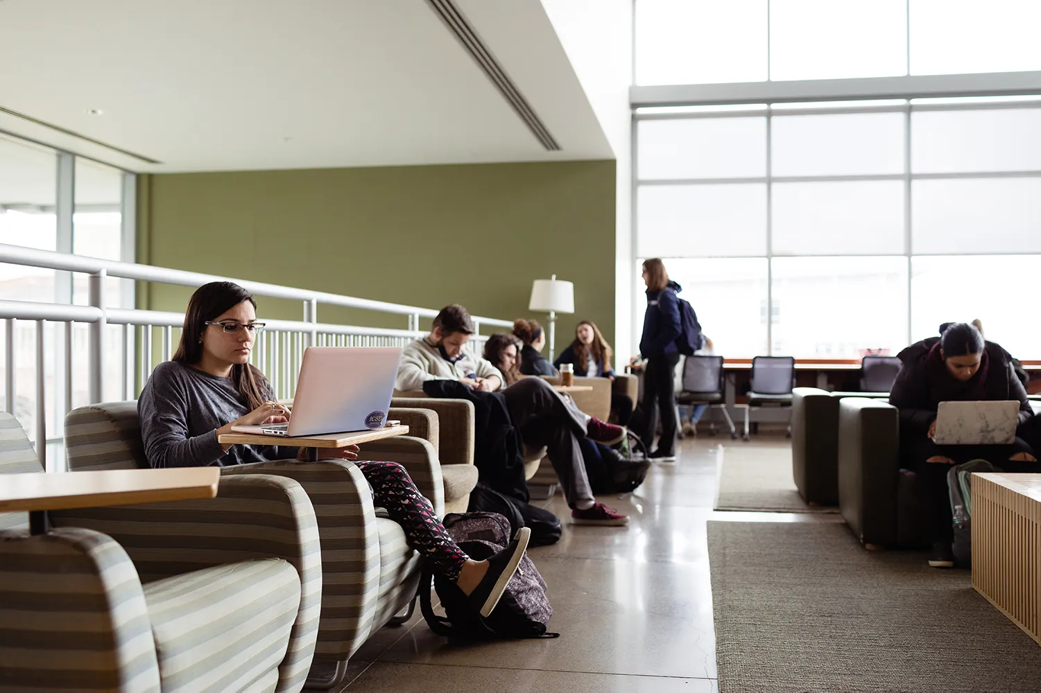 Students sit and study in chairs in a spacious, well-lit atrium. 
