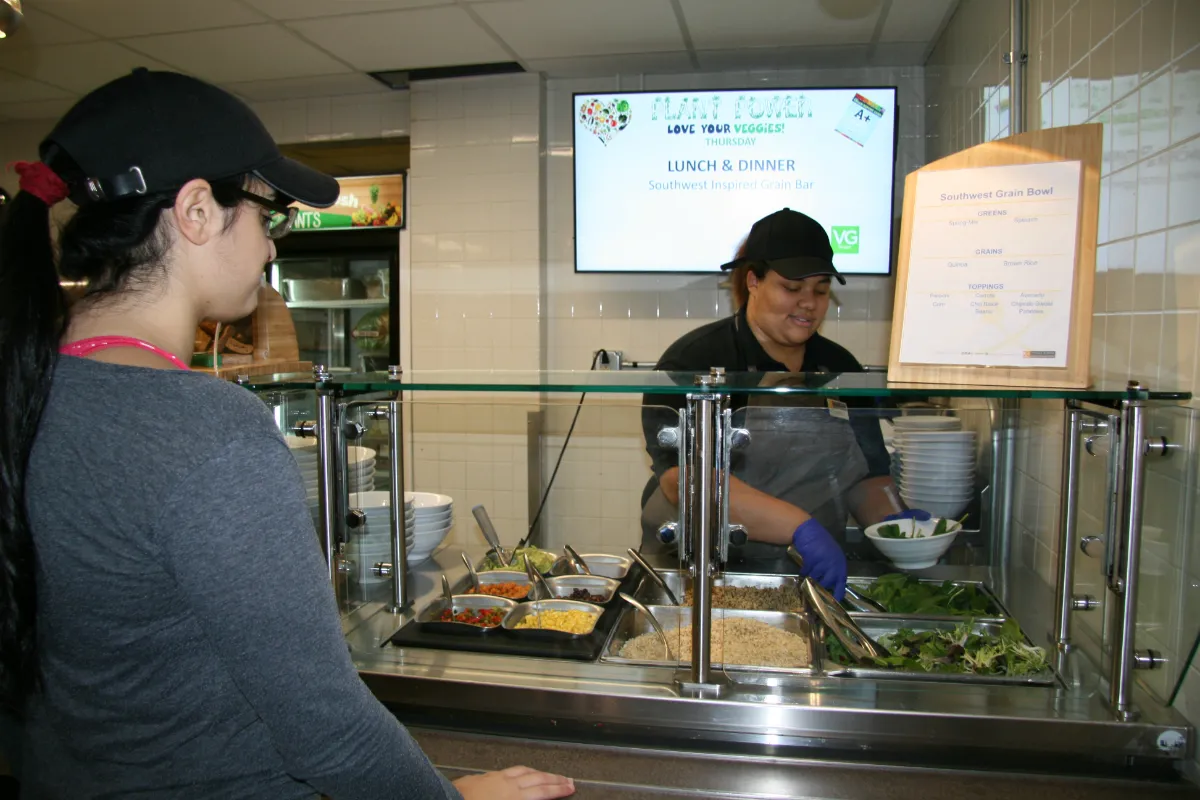 A woman at a counter puts food in a bowl