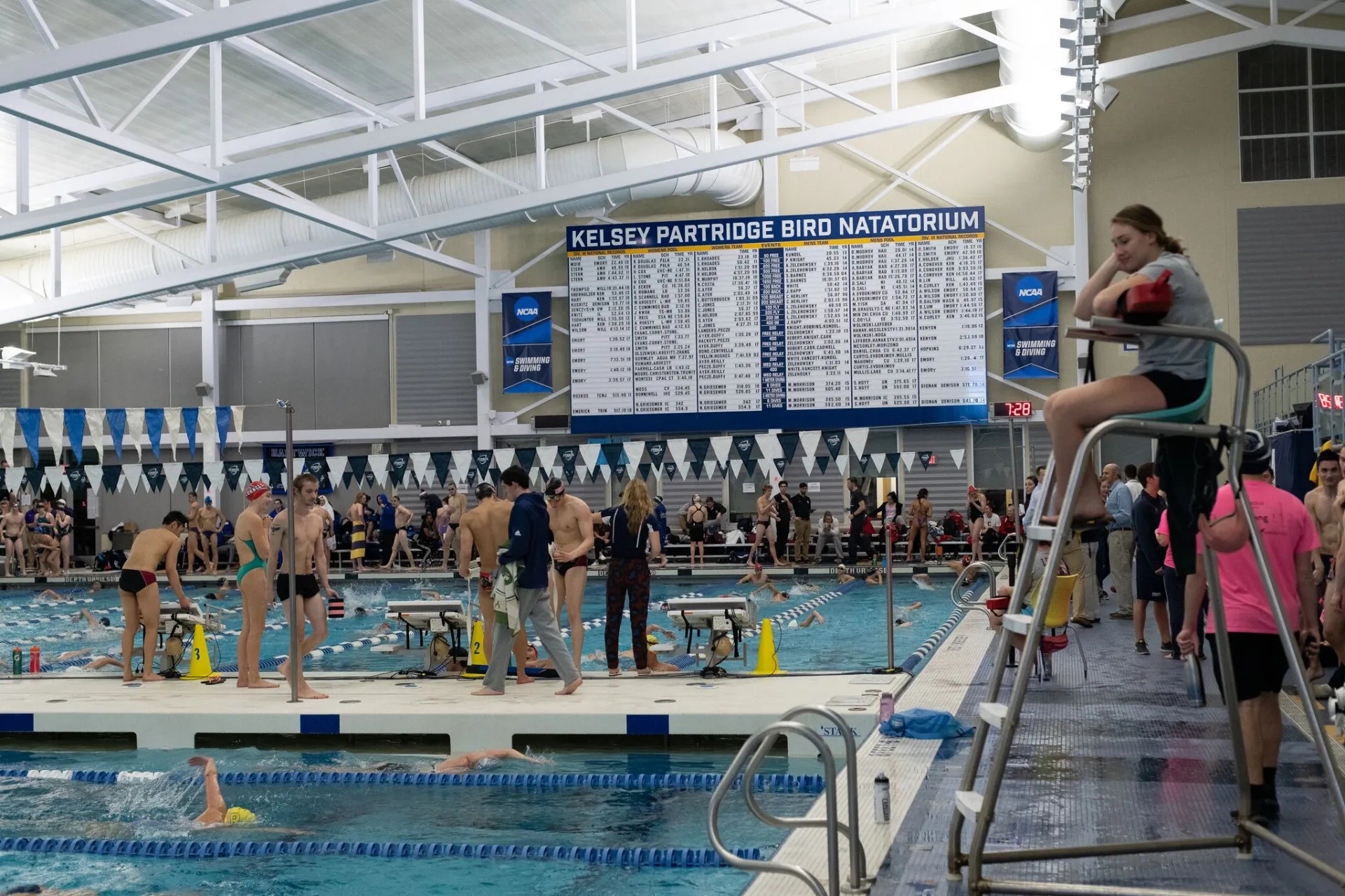 Signage that reads Kelsey Partridge Bird Natatorium over swimmers in the pool