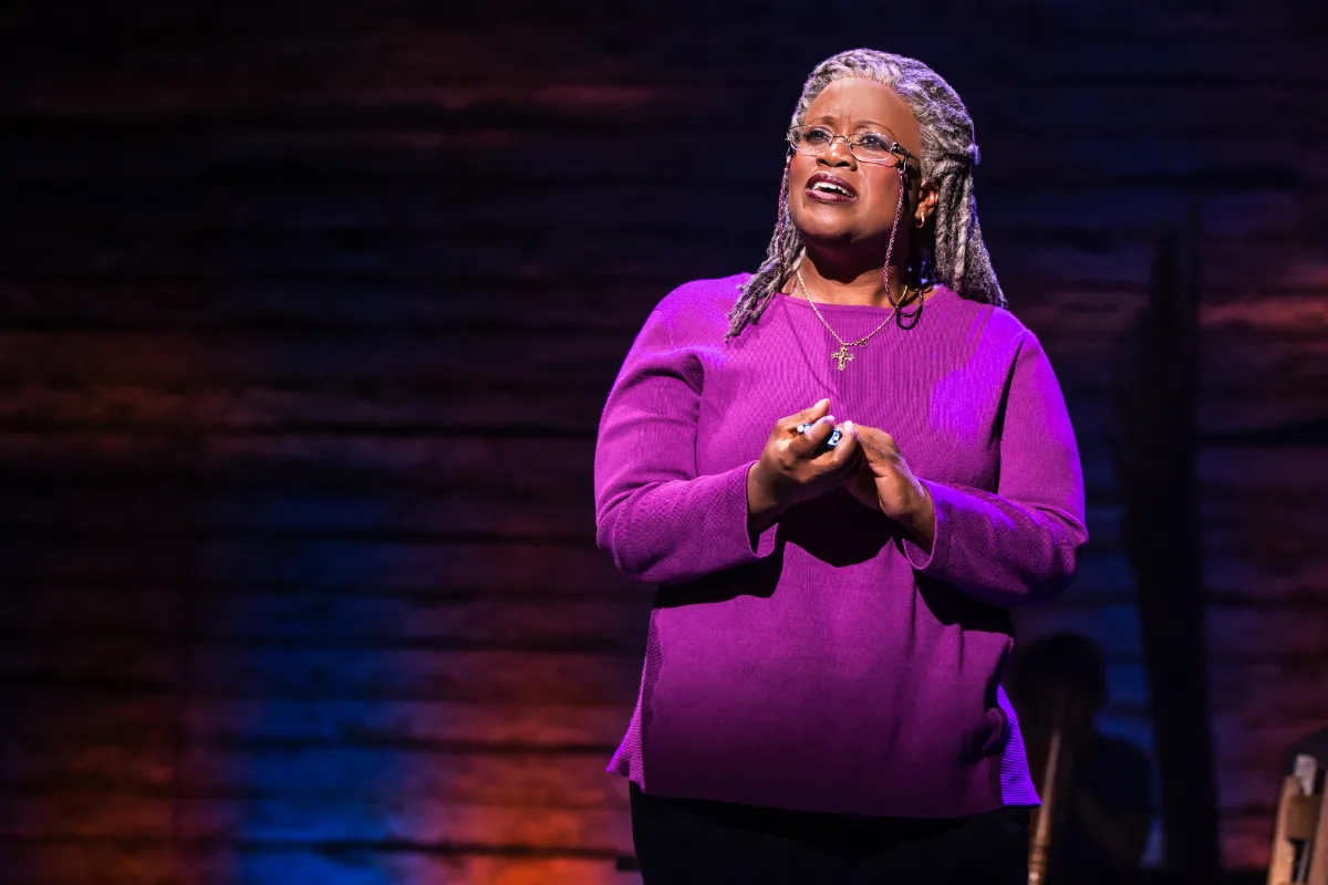 A black woman with long grey hair on stage