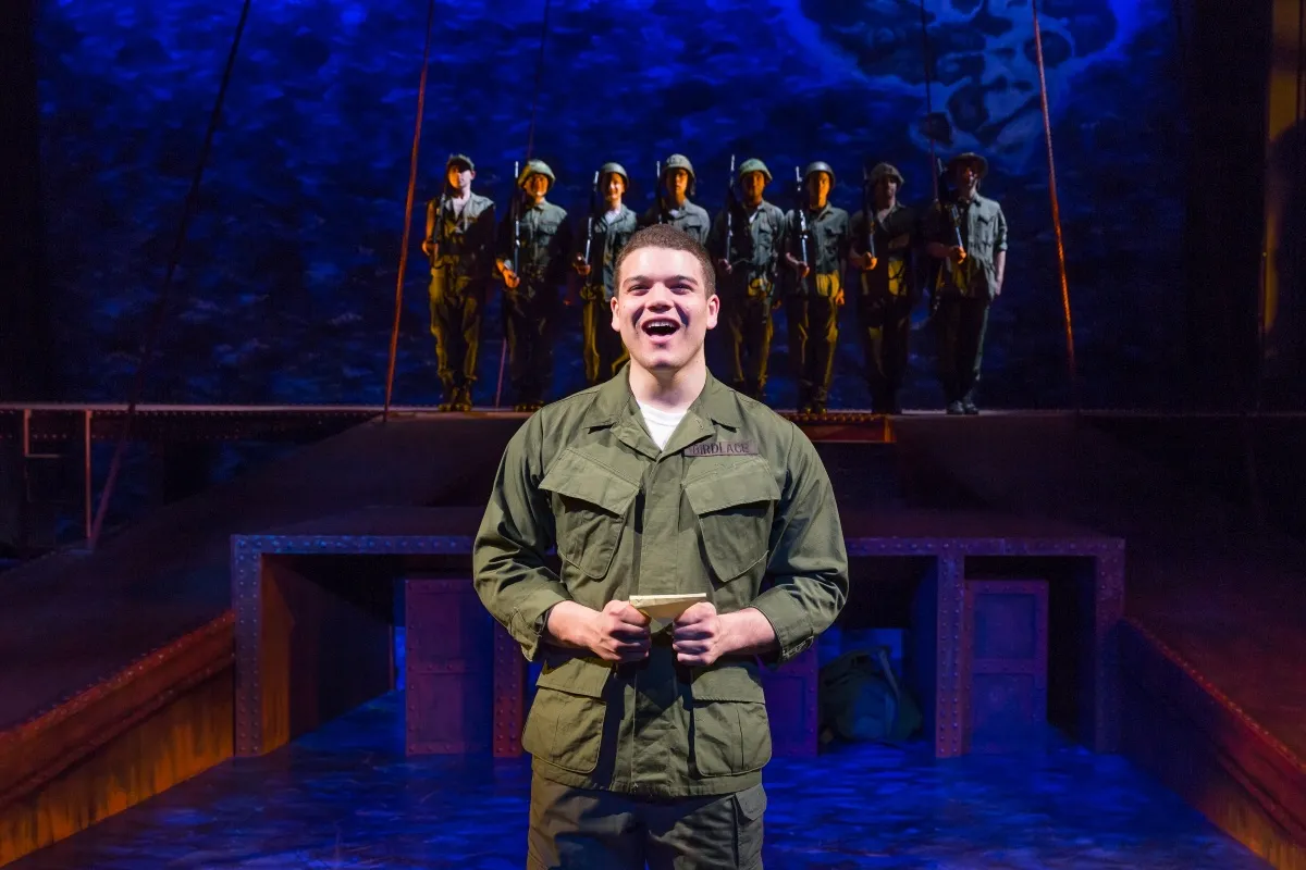 A man in military fatigues sings on stage