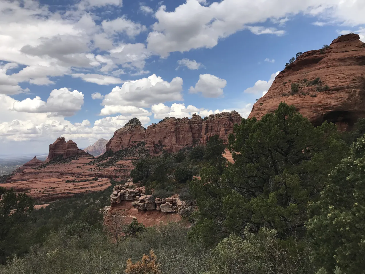 A scenic desert landscape in the southwest United States, featuring shrubby vegetation and towering red rocks