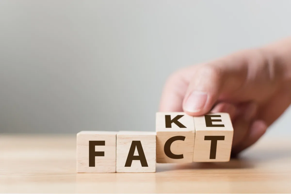 A hand moving lettered blocks spelling FAKE to FACT