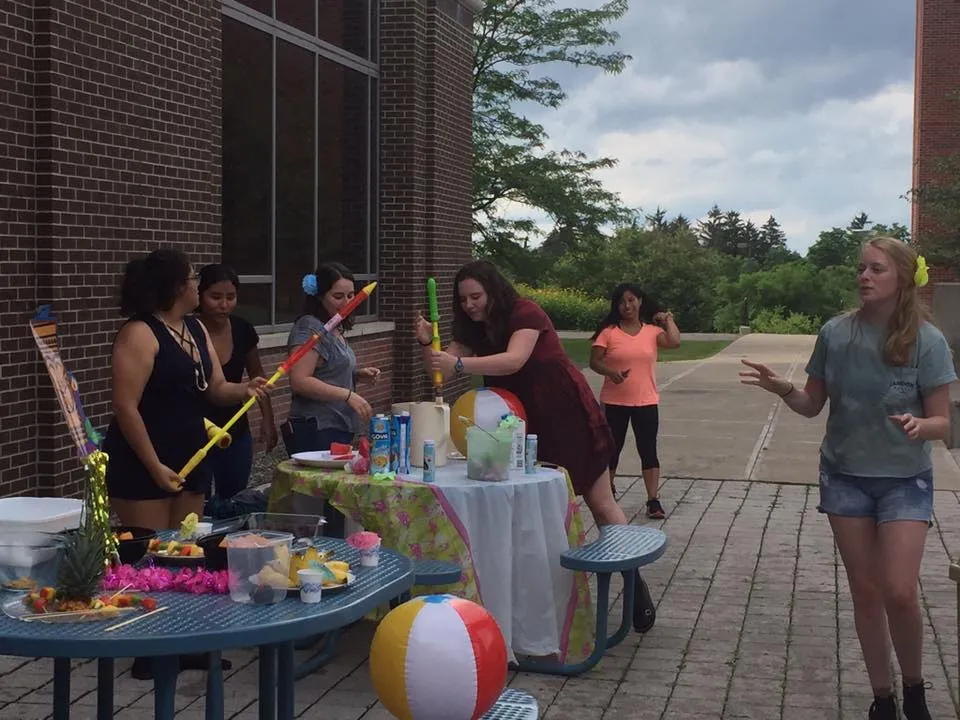 a group of students outside at a party with squirt guns and beach balls