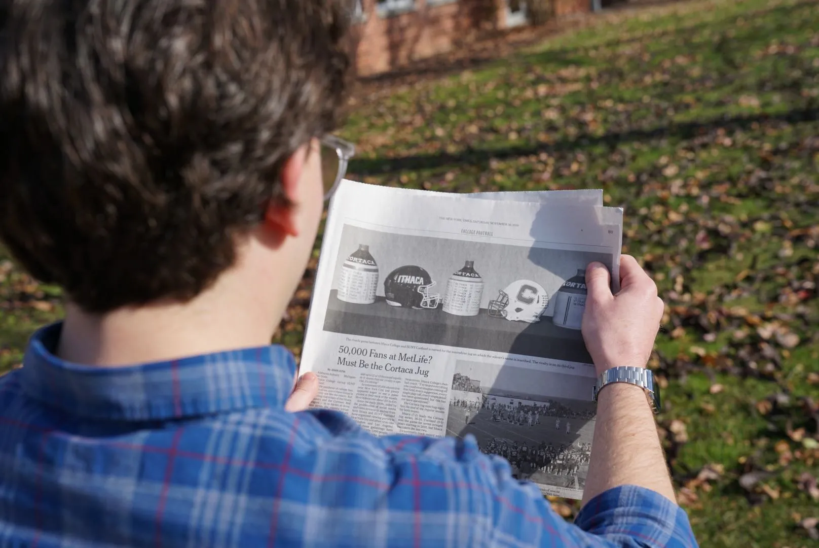 A young man reading a newspaper outside