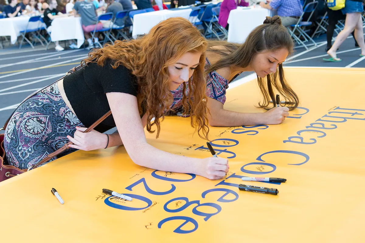 two women sign a banner