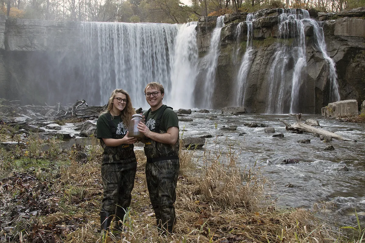 students taking water samples near a waterfall