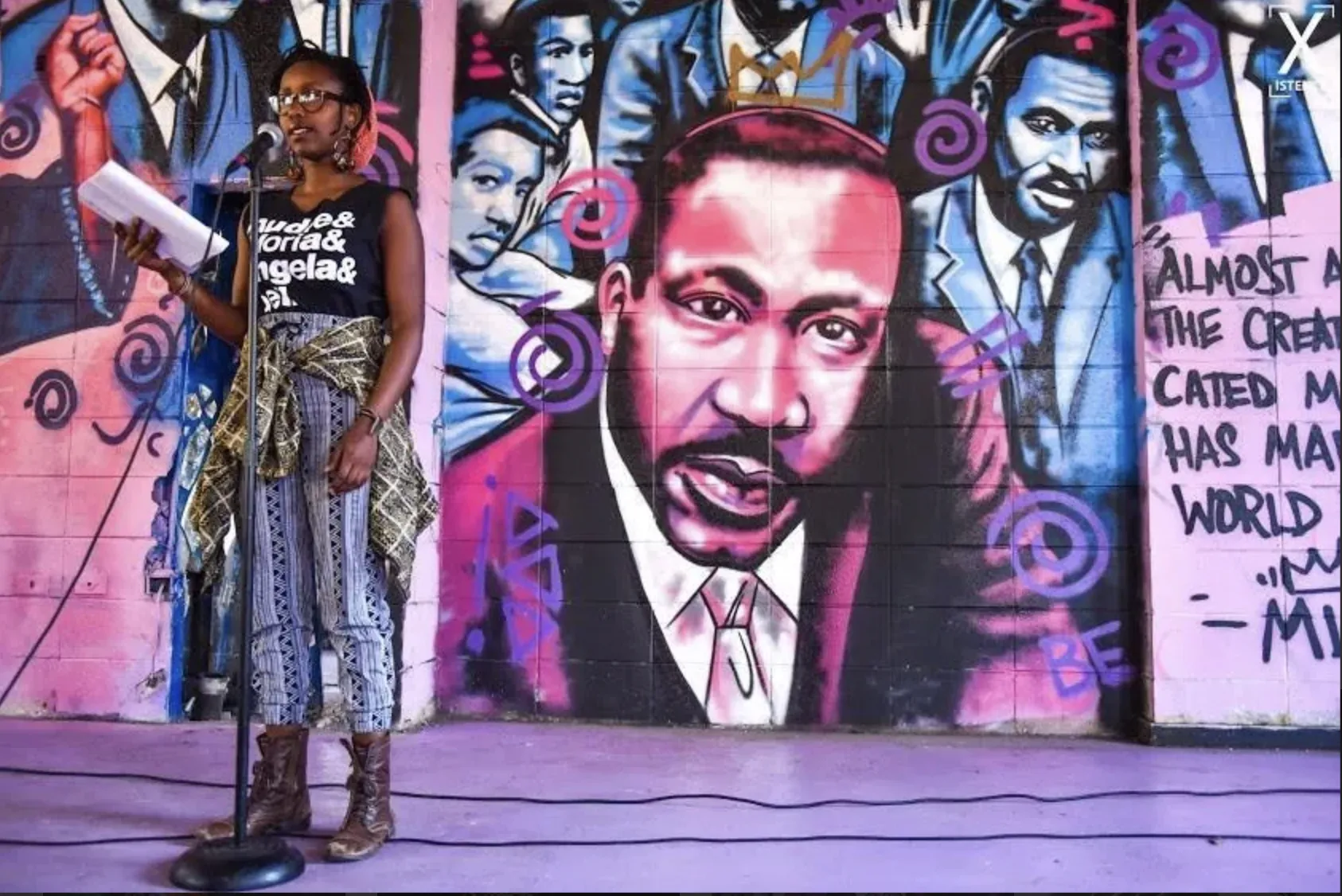 spoken word poet in front of a mural