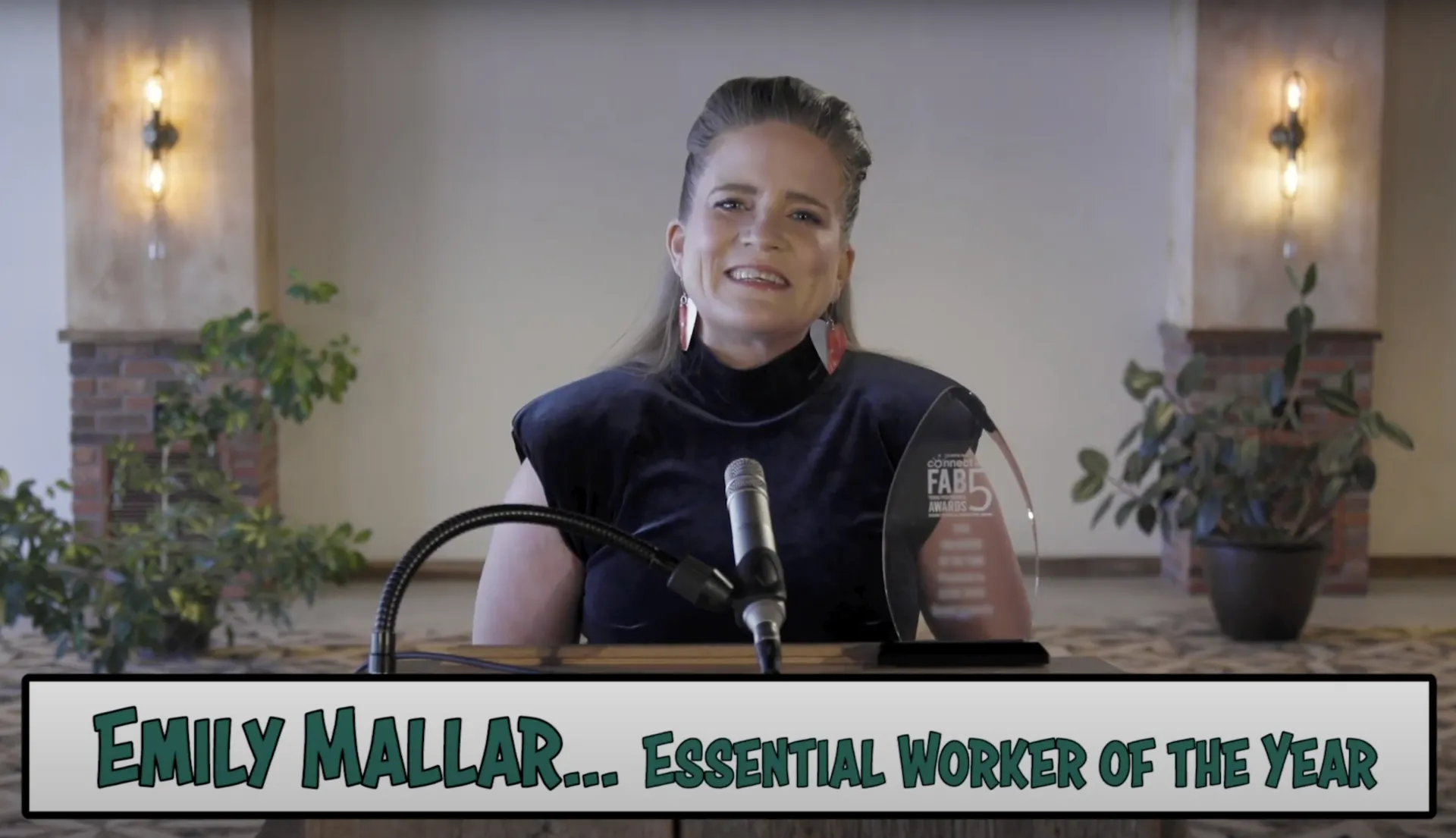 Woman receiving award with the text "Emily Maller: Essential Worker of the Year"