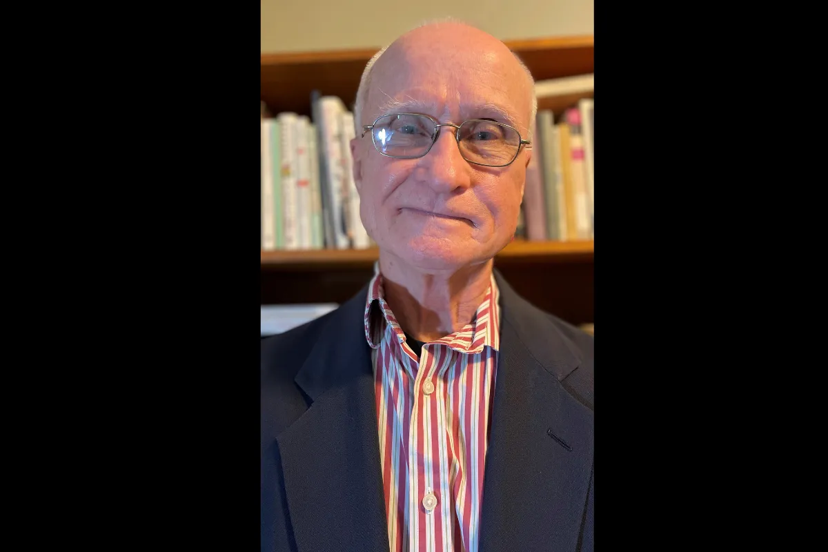 Bernard Beins standing in front of a bookshelf