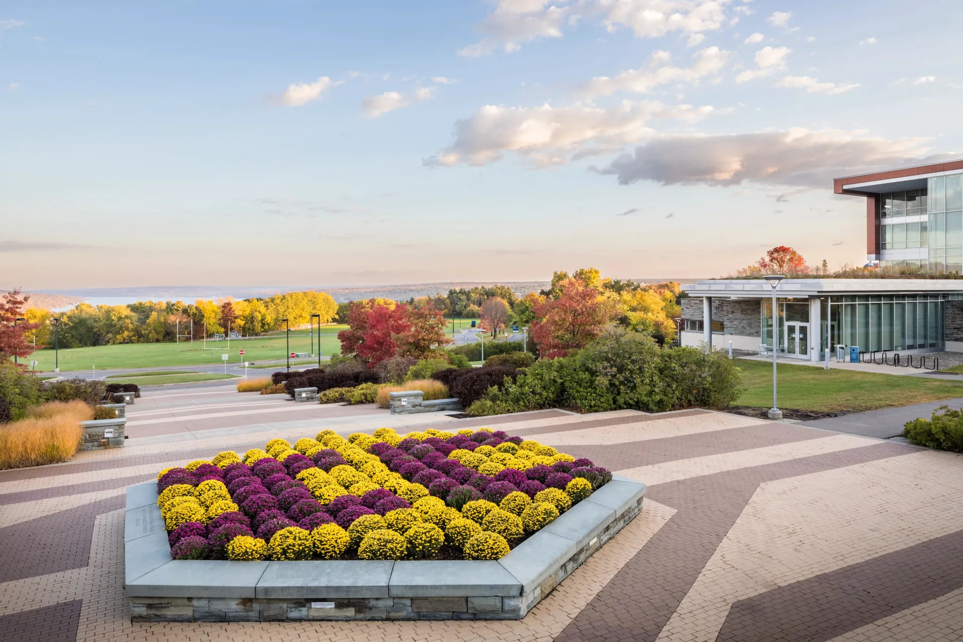 A photo of a flower bed with "IC" in it overlooking a green lawn and the lake in the distance.