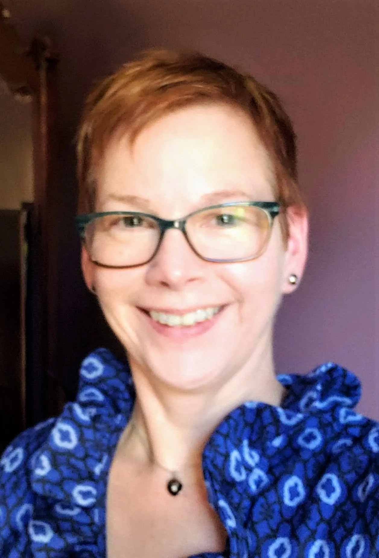 Woman with pale skin, short reddish hair, glasses